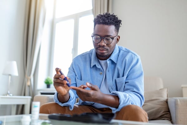 Black man takes blood sugar reading by poking finger 490851219