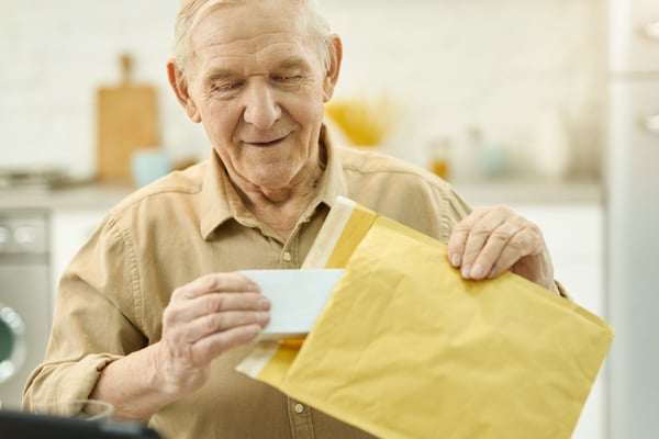 Elderly man opening package with medication in it_410342697