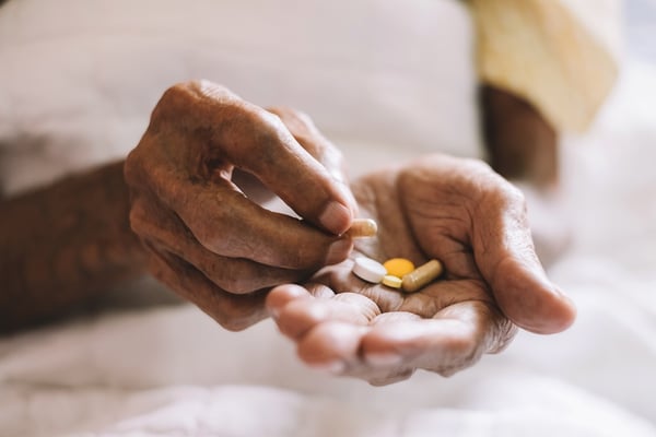 close up of hands holding pills for daily medication regimen