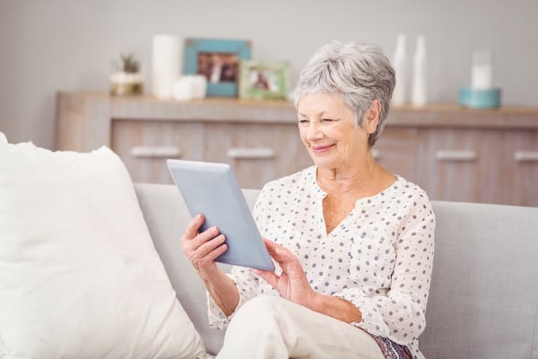 elderly woman using a tablet to reach out to a remote pharamcist and access care through telepharmacy