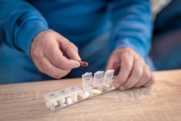 patient taking medication from daily pill organizer